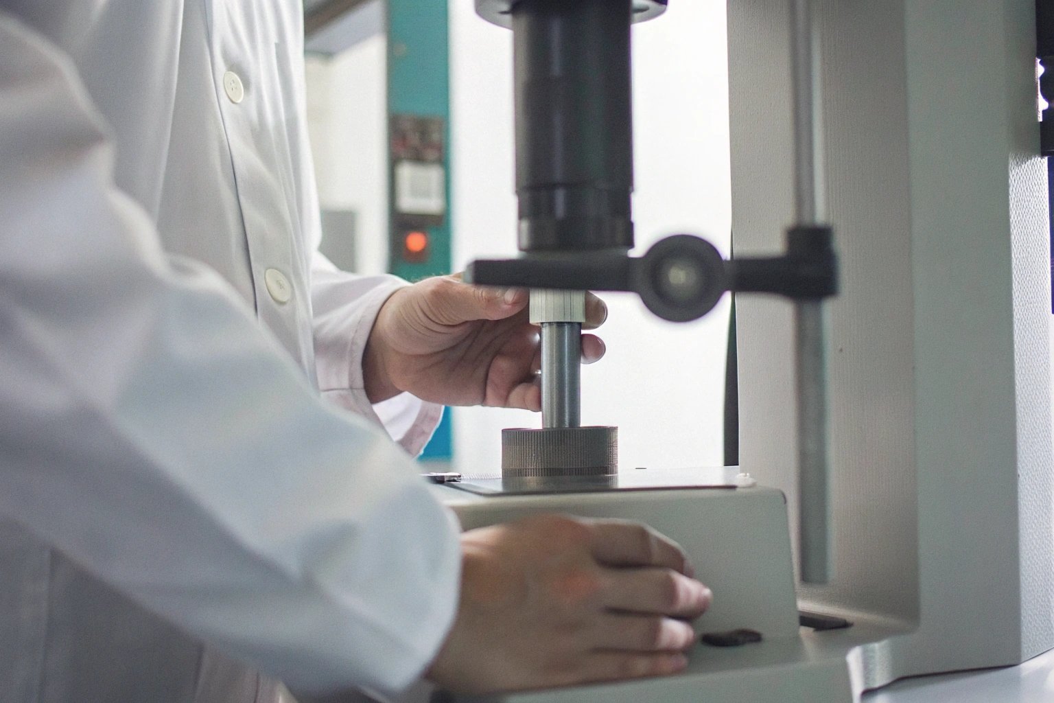 Lab technician using a hardness tester on a metal sheet